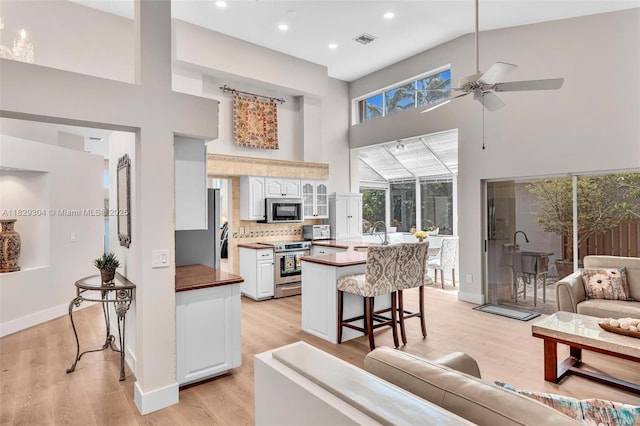 321 NW 100th Ave, Plantation, FL 33324 - kitchen featuring stainless steel appliances, a high ceiling, a kitchen breakfast bar, ceiling fan, and light wood-type flooring