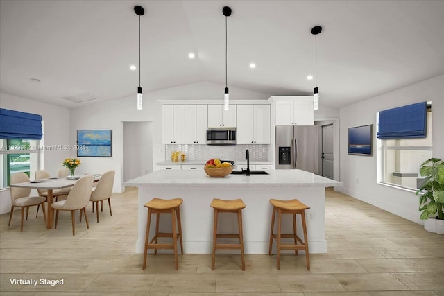 1301 NE 36th Ln, Cape Coral, FL 33909 - kitchen featuring appliances with stainless steel finishes, backsplash, a center island with sink, white cabinetry, and a kitchen breakfast bar