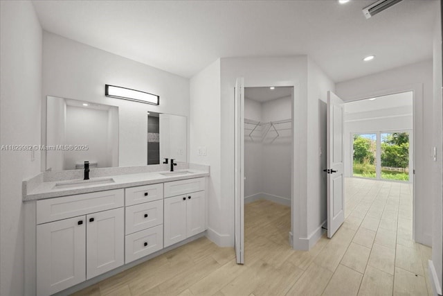 1301 NE 36th Ln, Cape Coral, FL 33909 - bathroom featuring double vanity, wood finished floors, a spacious closet, and recessed lighting