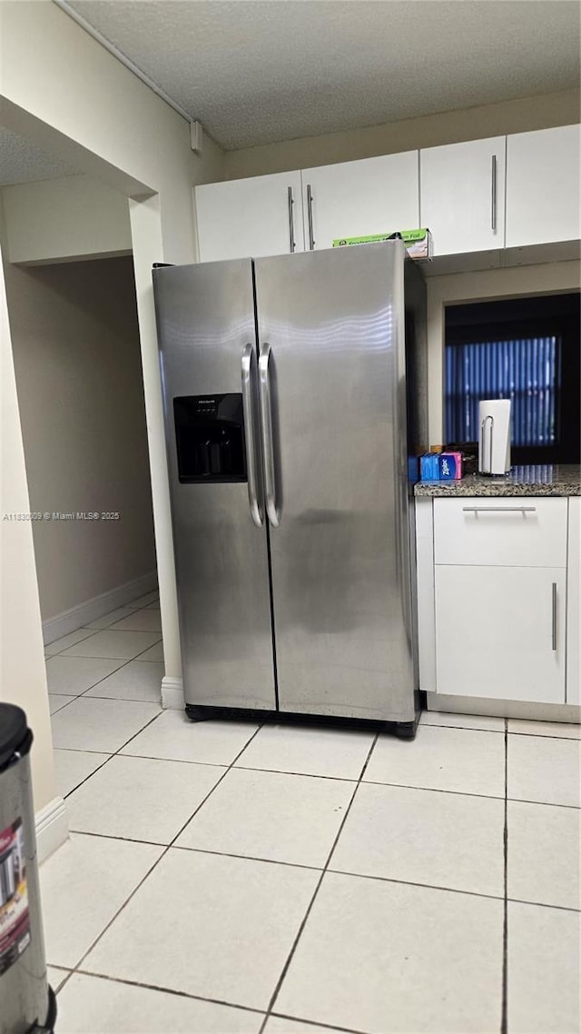 7500 NW 17th St Unit 101, Plantation, FL 33313 - kitchen featuring stainless steel refrigerator with ice dispenser, white cabinets, light tile patterned floors, a textured ceiling, and dark stone counters