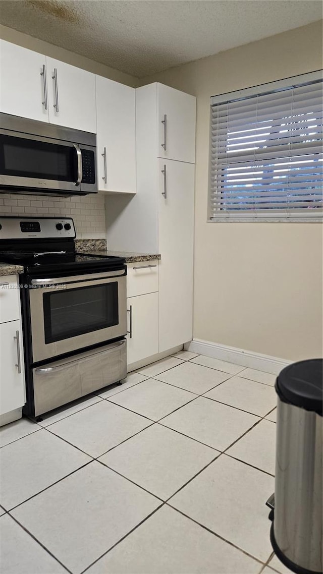 7500 NW 17th St Unit 101, Plantation, FL 33313 - kitchen featuring appliances with stainless steel finishes, white cabinets, a textured ceiling, backsplash, and light tile patterned floors
