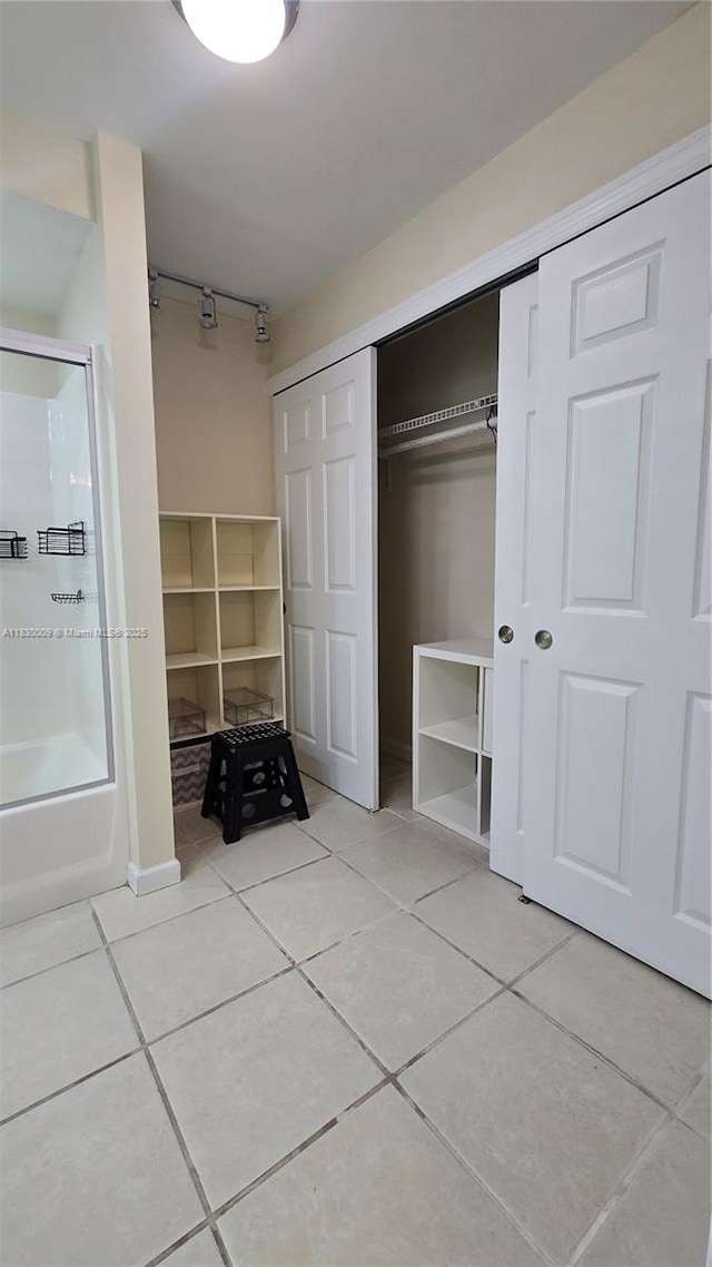 7500 NW 17th St Unit 101, Plantation, FL 33313 - full bathroom featuring tile patterned floors, rail lighting, combined bath / shower with glass door, and a spacious closet