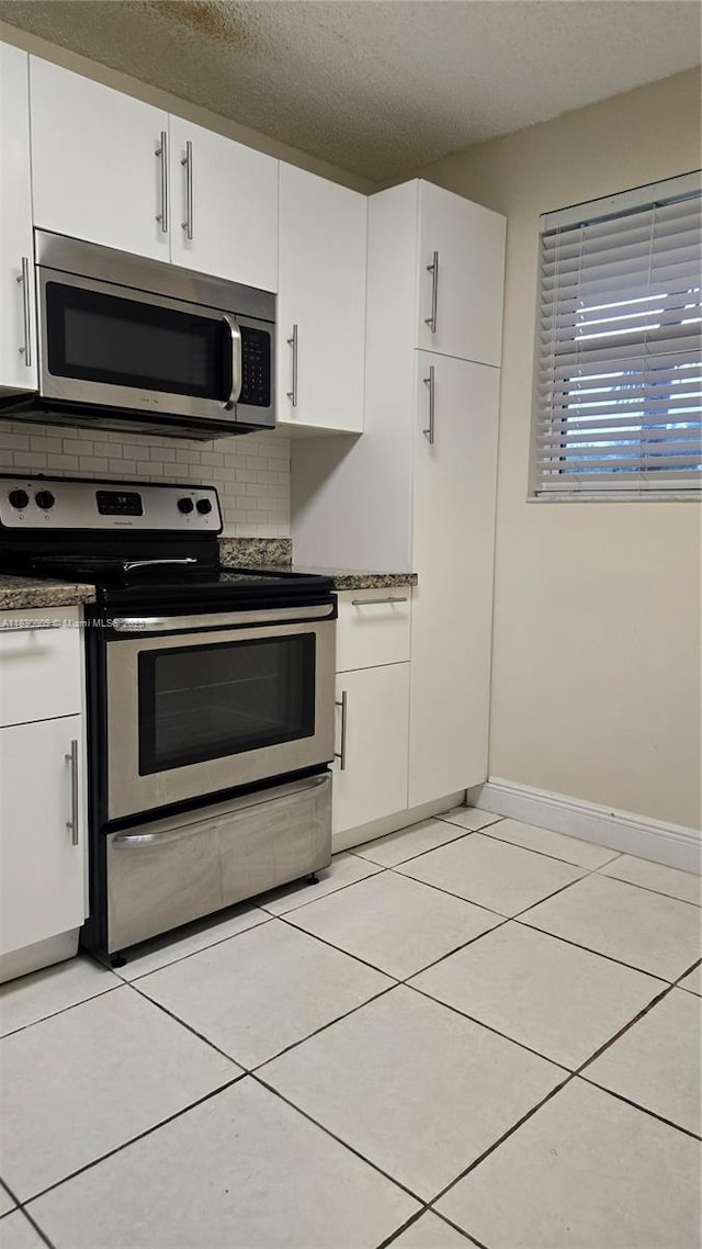 7500 NW 17th St Unit 101, Plantation, FL 33313 - kitchen featuring appliances with stainless steel finishes, backsplash, white cabinets, light tile patterned flooring, and a textured ceiling
