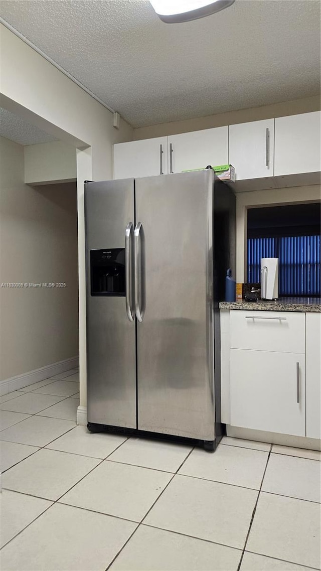 7500 NW 17th St Unit 101, Plantation, FL 33313 - kitchen featuring stainless steel fridge, white cabinets, light tile patterned flooring, a textured ceiling, and dark stone countertops
