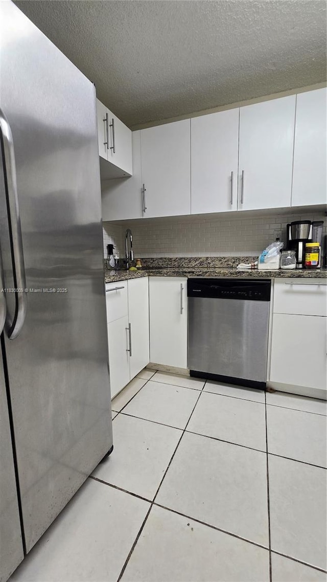 7500 NW 17th St Unit 101, Plantation, FL 33313 - kitchen featuring appliances with stainless steel finishes, backsplash, white cabinetry, a textured ceiling, and light tile patterned floors