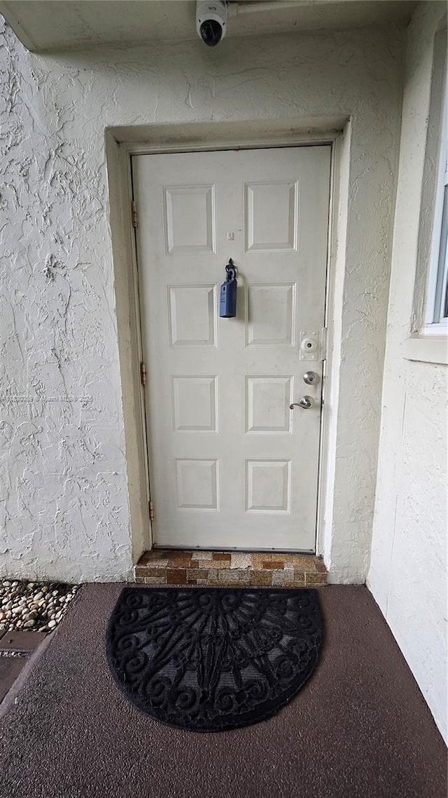 7500 NW 17th St Unit 101, Plantation, FL 33313 - view of exterior entry with stucco siding and a surveillance system
