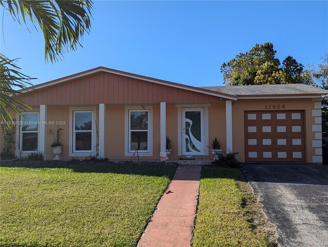 11024 SW 157th Ter, Miami, FL 33157 - view of front facade with an attached garage, driveway, a front yard, and stucco siding