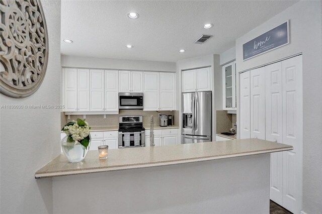 5347 SW 32nd Ter, Hollywood, FL 33312 - kitchen with stainless steel appliances, recessed lighting, white cabinets, a peninsula, and a textured ceiling