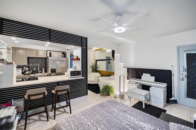1060 Pennsylvania Ave Unit 7, Miami Beach, FL 33139 - kitchen featuring stainless steel refrigerator with ice dispenser, white microwave, light tile patterned floors, a ceiling fan, and a breakfast bar
