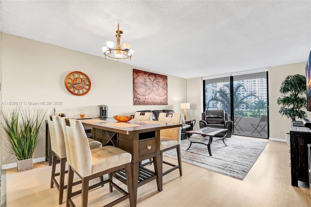500 Three Islands Blvd Unit 320, Hallandale Beach, FL 33009 - dining room featuring light wood finished floors, a chandelier, a textured ceiling, and expansive windows