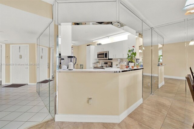 10217 NW 24th Pl Unit 310, Sunrise, FL 33322 - kitchen featuring appliances with stainless steel finishes, light tile patterned floors, white cabinets, a peninsula, and pendant lighting