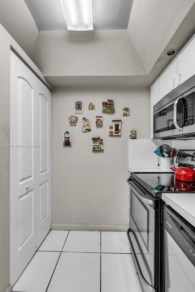 1345 Lincoln Rd Unit 1005, Miami Beach, FL 33139 - kitchen featuring stainless steel appliances, light tile patterned flooring, light countertops, white cabinets, and vaulted ceiling