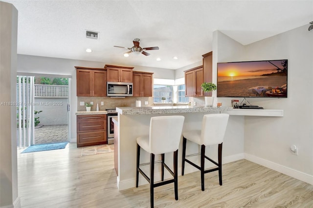 13552 NW 5th Ct, Plantation, FL 33325 - kitchen featuring stainless steel appliances, light wood-type flooring, healthy amount of natural light, brown cabinetry, and recessed lighting