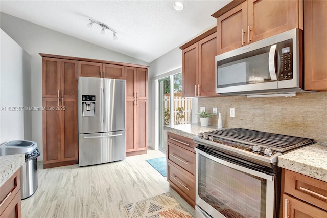 13552 NW 5th Ct, Plantation, FL 33325 - kitchen featuring stainless steel appliances, vaulted ceiling, decorative backsplash, brown cabinets, and a textured ceiling