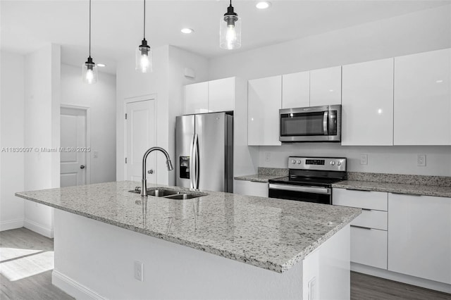 933 Gleason St, Lehigh Acres, FL 33974 - kitchen featuring appliances with stainless steel finishes, wood finished floors, white cabinets, a kitchen island with sink, and recessed lighting