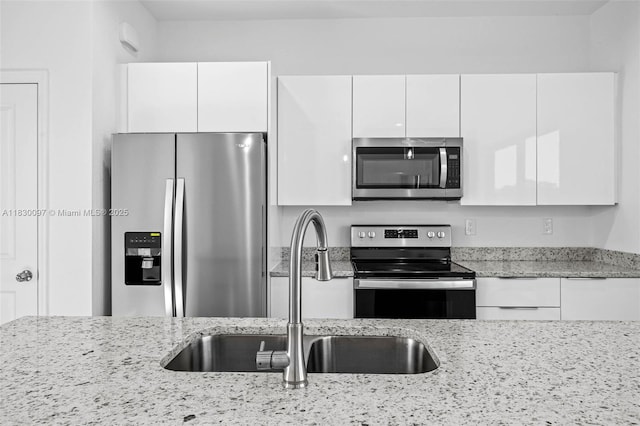 933 Gleason St, Lehigh Acres, FL 33974 - kitchen with appliances with stainless steel finishes, white cabinets, light stone countertops, and modern cabinets