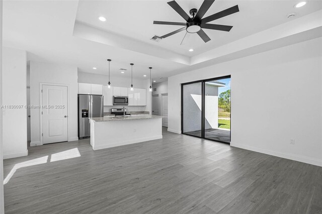 933 Gleason St, Lehigh Acres, FL 33974 - kitchen featuring stainless steel appliances, recessed lighting, a raised ceiling, white cabinetry, and an island with sink