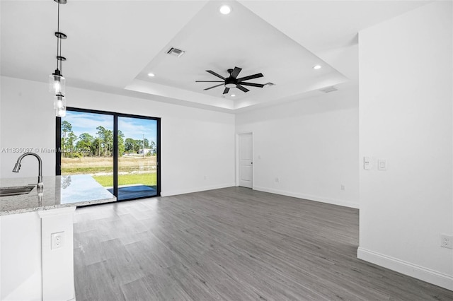 933 Gleason St, Lehigh Acres, FL 33974 - unfurnished living room with recessed lighting, ceiling fan, a tray ceiling, and wood finished floors