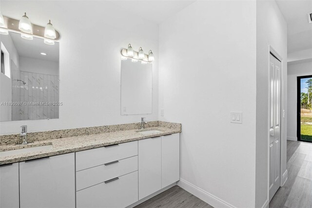 933 Gleason St, Lehigh Acres, FL 33974 - bathroom featuring double vanity, wood finished floors, and tiled shower