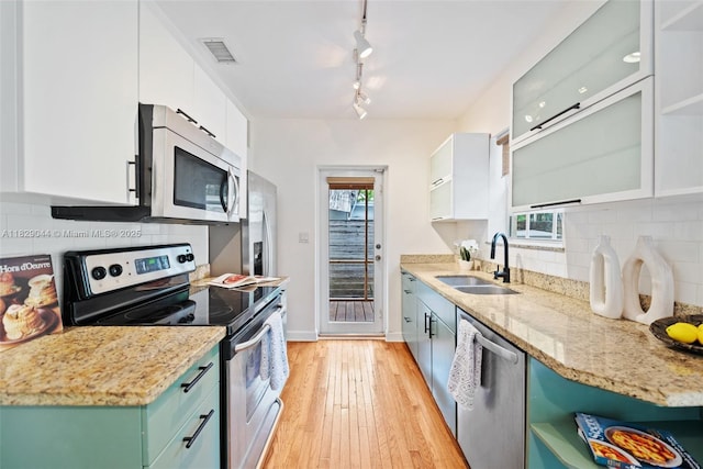 8325 NE 3rd Ave, Miami, FL 33138 - kitchen with appliances with stainless steel finishes, white cabinets, decorative backsplash, light wood finished floors, and healthy amount of natural light