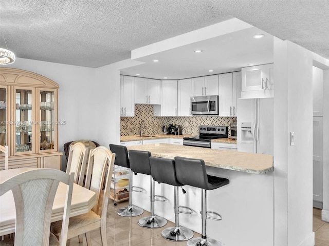 20401 NE 30th Ave Unit 310-8, Aventura, FL 33180 - kitchen featuring stainless steel appliances, white cabinetry, a textured ceiling, light tile patterned floors, and backsplash