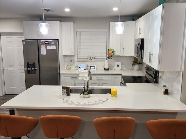 4356 S Mary Cir, Palm Beach Gardens, FL 33410 - kitchen with stainless steel appliances, decorative backsplash, a kitchen breakfast bar, white cabinets, and recessed lighting