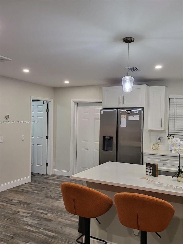4356 S Mary Cir, Palm Beach Gardens, FL 33410 - kitchen with stainless steel fridge, white cabinetry, light countertops, dark wood-style floors, and a breakfast bar