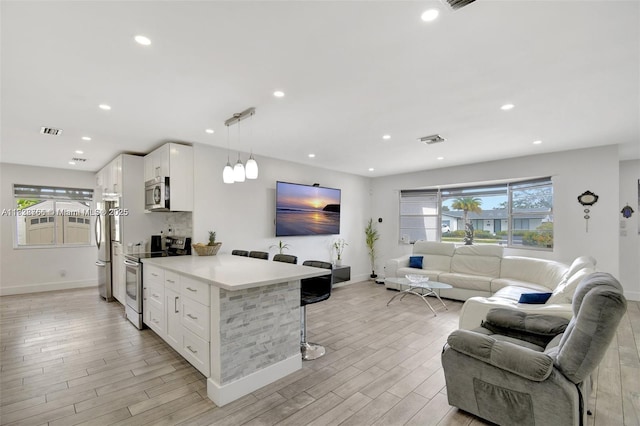 1840 N 56th Ave, Hollywood, FL 33021 - kitchen featuring appliances with stainless steel finishes, open floor plan, a breakfast bar, white cabinets, and light wood-style flooring