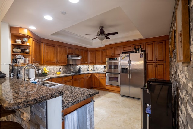 9 NE 20th Ave Unit 201, Deerfield Beach, FL 33441 - kitchen with stainless steel appliances, a tray ceiling, under cabinet range hood, a peninsula, and brown cabinets