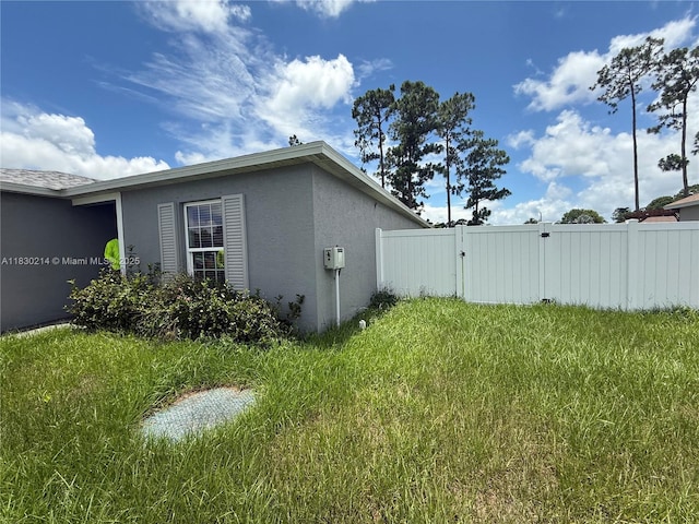 3574 SW Masilunas St, Port St Lucie, FL 34953 - view of property exterior featuring stucco siding and a gate