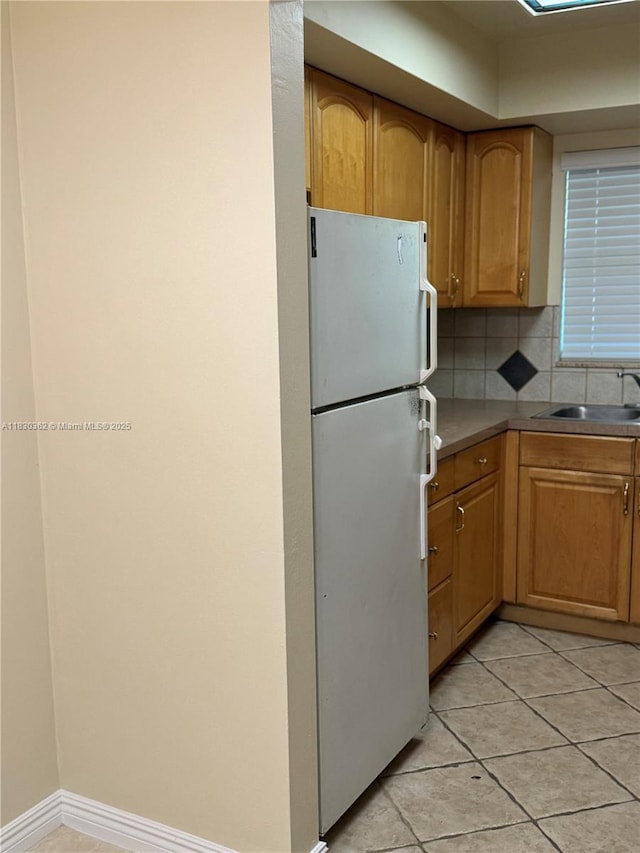 3500 Harrison St Unit 10, Hollywood, FL 33021 - kitchen with freestanding refrigerator, light tile patterned flooring, decorative backsplash, and brown cabinetry