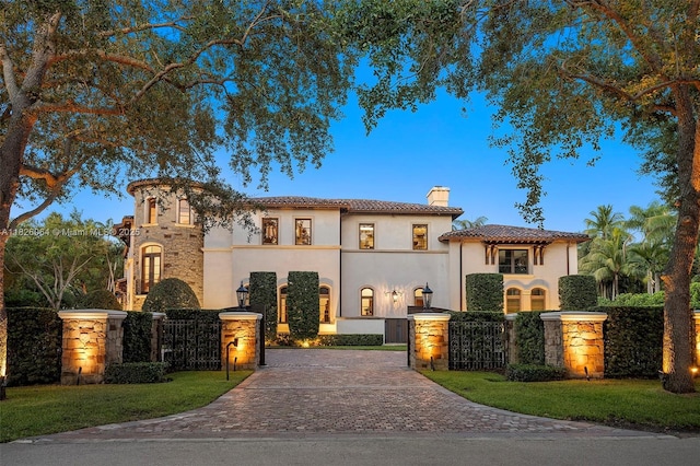 10101 SW 60th Ct, Pinecrest, FL 33156 - mediterranean / spanish-style house featuring a chimney, decorative driveway, stucco siding, and a tile roof