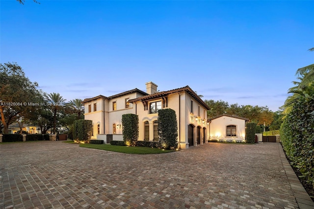 10101 SW 60th Ct, Pinecrest, FL 33156 - mediterranean / spanish-style home featuring stucco siding, curved driveway, a chimney, and a tiled roof