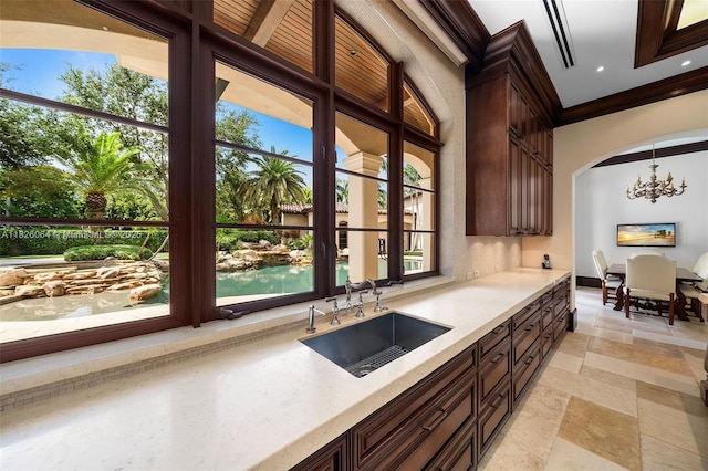 10101 SW 60th Ct, Pinecrest, FL 33156 - kitchen featuring light countertops, a chandelier, stone tile flooring, dark brown cabinets, and ornamental molding