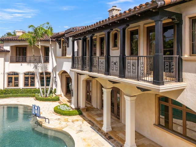 10101 SW 60th Ct, Pinecrest, FL 33156 - back of house with a chimney, a balcony, stucco siding, and a patio