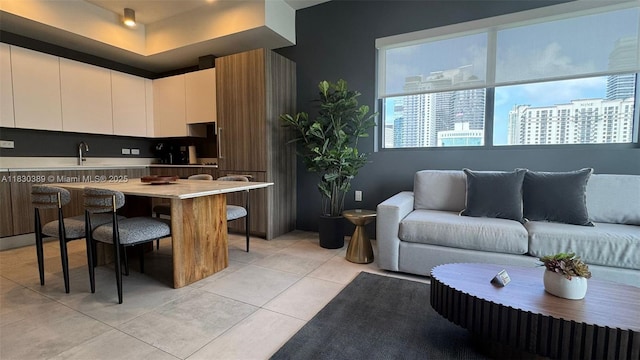 239 SW 9th St Unit 1604, Miami, FL 33130 - kitchen with light countertops, white cabinetry, light tile patterned flooring, a kitchen bar, and open floor plan