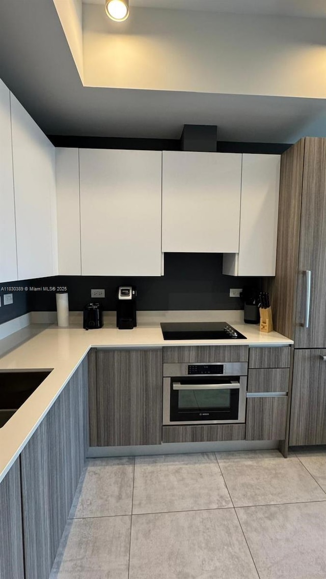 239 SW 9th St Unit 1604, Miami, FL 33130 - kitchen with stainless steel oven, black electric stovetop, modern cabinets, and light tile patterned flooring