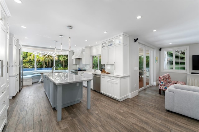11401 SW 69th Ave, Pinecrest, FL 33156 - kitchen with high quality appliances, custom range hood, dark wood finished floors, a kitchen island with sink, and white cabinetry