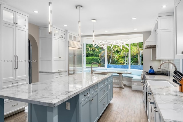 11401 SW 69th Ave, Pinecrest, FL 33156 - kitchen with stainless steel built in fridge, white cabinets, stove, arched walkways, and custom range hood