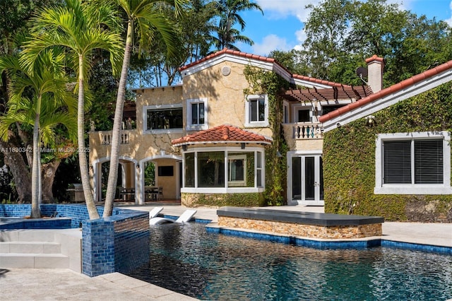 11401 SW 69th Ave, Pinecrest, FL 33156 - back of property featuring a balcony, a tiled roof, an outdoor pool, stucco siding, and a patio area