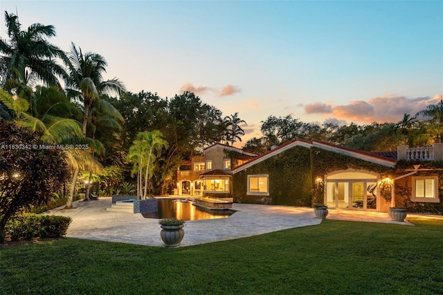 11401 SW 69th Ave, Pinecrest, FL 33156 - back of house at dusk with french doors, a patio, a lawn, and an outdoor pool