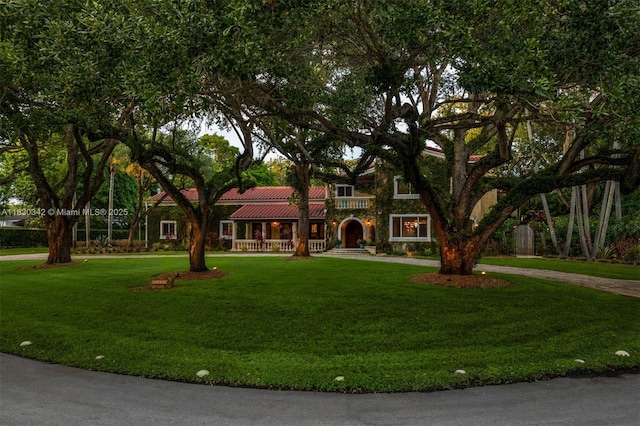 11401 SW 69th Ave, Pinecrest, FL 33156 - view of front facade with covered porch, a tiled roof, a front lawn, and curved driveway