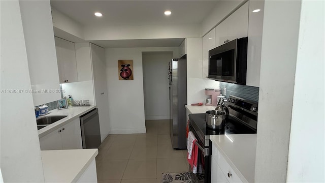16546 NE 26th Ave Unit 4I, North Miami Beach, FL 33160 - kitchen with stainless steel appliances, white cabinets, light countertops, tasteful backsplash, and light tile patterned floors