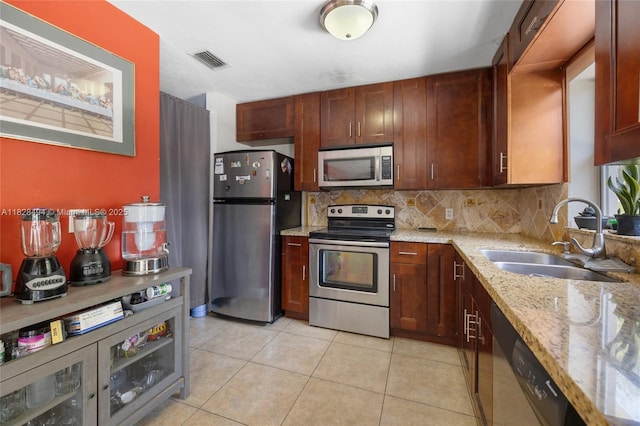 4960 SW 5th St, Margate, FL 33068 - kitchen with appliances with stainless steel finishes, decorative backsplash, light stone counters, and light tile patterned floors