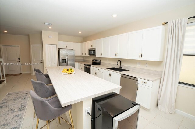 25433 SW 108th Ct, Homestead, FL 33032 - kitchen featuring appliances with stainless steel finishes, light tile patterned flooring, a kitchen island, a breakfast bar, and white cabinets