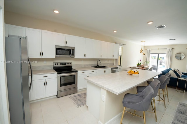 25433 SW 108th Ct, Homestead, FL 33032 - kitchen featuring stainless steel appliances, white cabinets, a breakfast bar area, light countertops, and recessed lighting