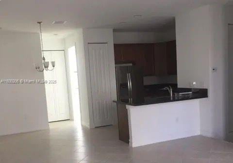 11332 SW 15th St, Pembroke Pines, FL 33025 - kitchen featuring dark countertops, a peninsula, stainless steel fridge, decorative light fixtures, and a chandelier