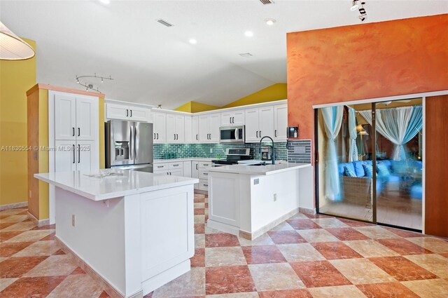 450 NW 195th Ave, Pembroke Pines, FL 33029 - kitchen with stainless steel appliances, a peninsula, tasteful backsplash, lofted ceiling, and light countertops