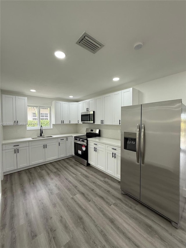 6201 SW 20th Ct, Miramar, FL 33023 - kitchen featuring stainless steel appliances, recessed lighting, light countertops, white cabinetry, and light wood-style floors