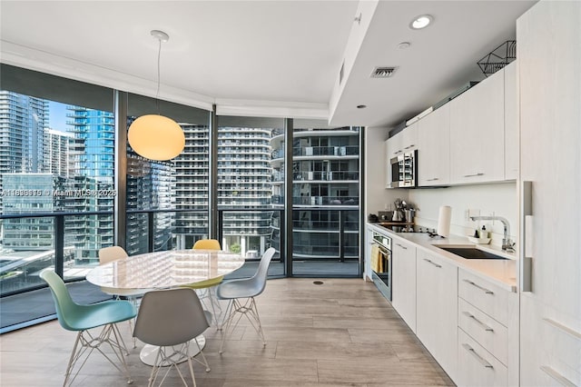 55 SW 9th St Unit 1801, Miami, FL 33130 - kitchen featuring floor to ceiling windows, stainless steel microwave, light wood finished floors, black electric stovetop, and white cabinets